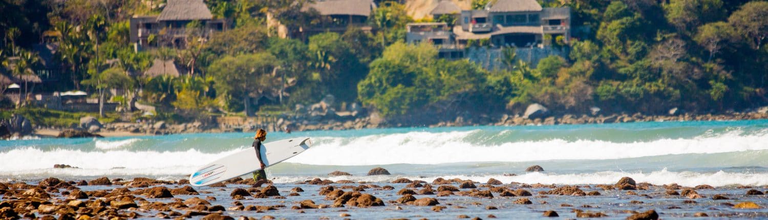 Surfer with board heading into the water in Riviera Nayarit Mexico